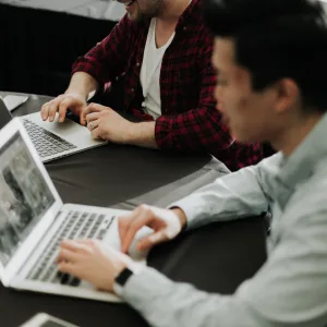 Photo: Two men working on their laptops together.