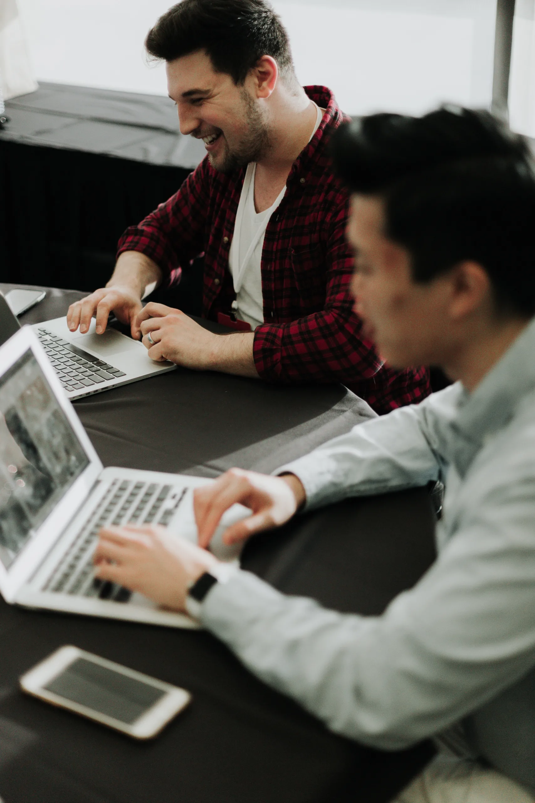 Photo: Two men working on their laptops together.