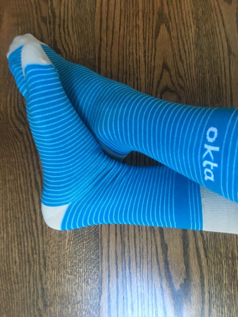Photograph of blue and white striped socks with Okta brand logo.
