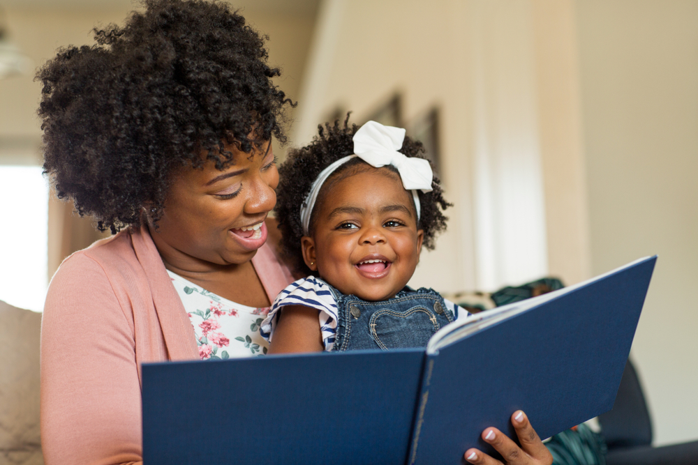 Photograph of a mother reading a book to her toddler daughter via shutterstock.