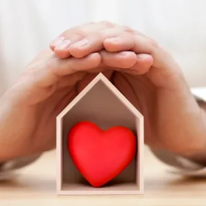 Photo: Hands cradle a house-shaped box with red heart inside
