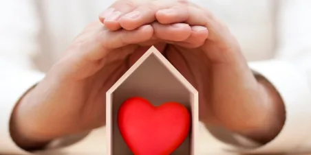 Photo: Hands cradle a house-shaped box with red heart inside