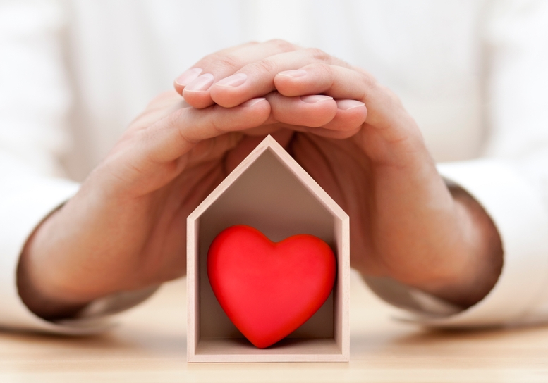 Photo: Hands cradle a house-shaped box with red heart inside