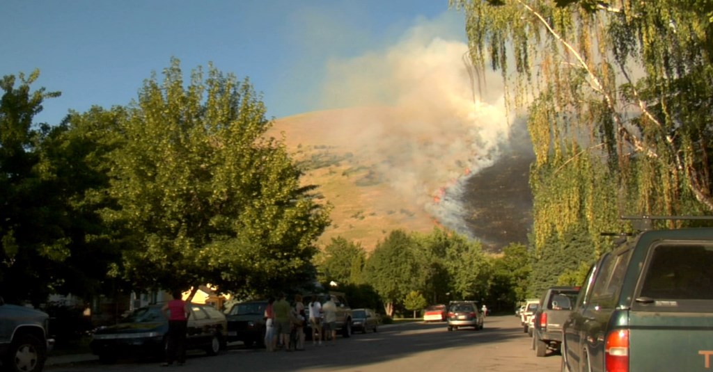 Phot: Grassy hillside burning as residents watch from the road.