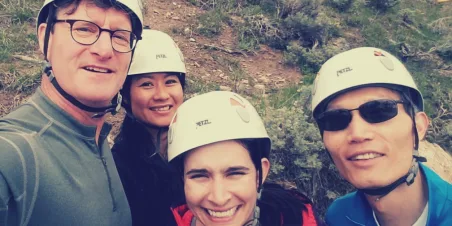 Photo: Smiling Team in safety helmets about to zipline together. Salesforce nonprofit consulting jobs