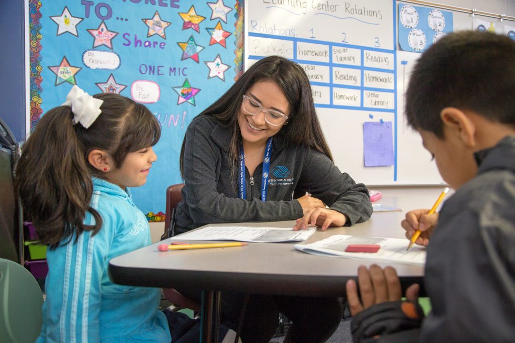 Photo: Instructor helping two children with skills worksheets.