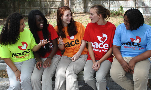 Photo: PACE students sitting on a bench talking and laughing. 