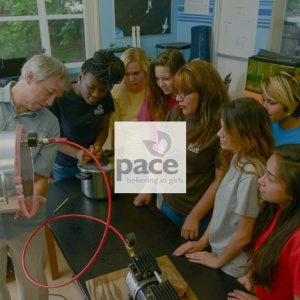 Photo with PACE logo: PACE students gather to watch science teacher conduct an experiment.