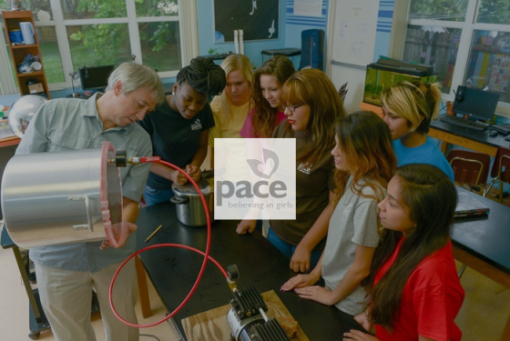 Photo with PACE logo: PACE students gather to watch science teacher conduct an experiment.