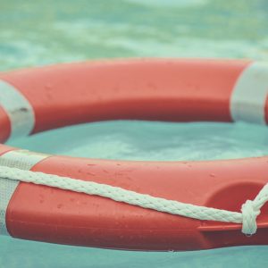 Photo: Orange and white life buoy floating at sea.