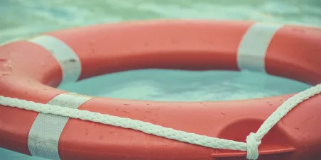 Photo: Orange and white life buoy floating at sea.