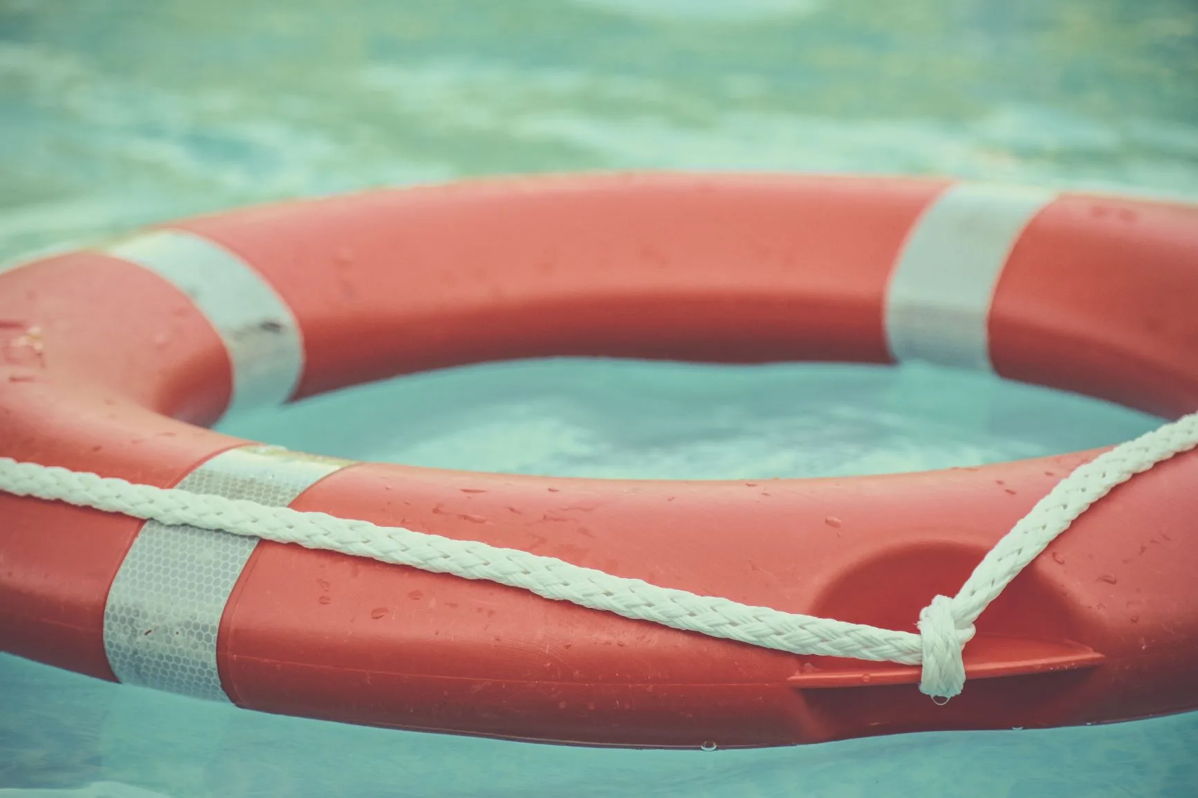 Photo: Orange and white life buoy floating at sea.