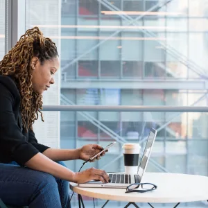 Photo: Woman with smartphone and coffee conducting remote work.