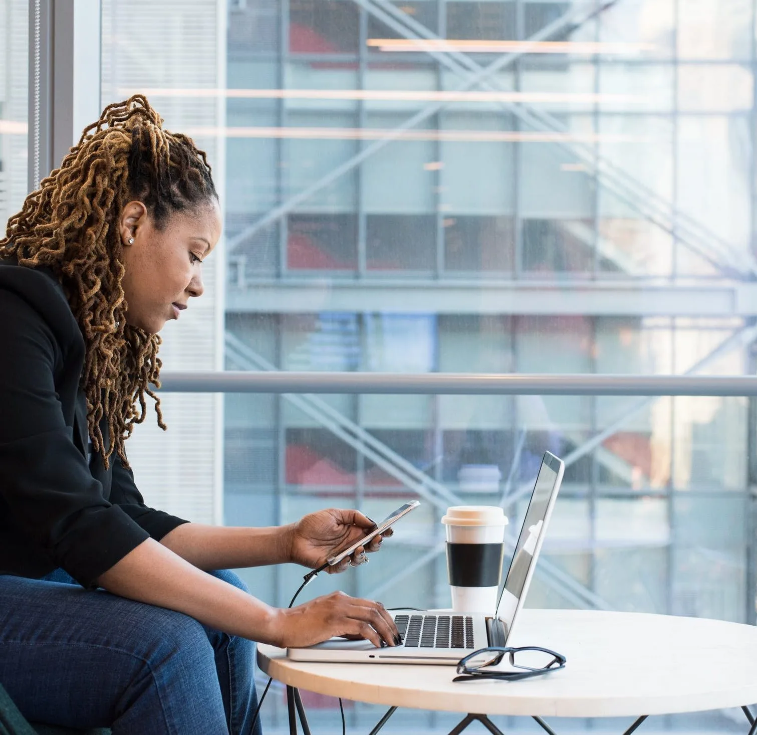 Photo: Woman with smartphone and coffee conducting remote work.