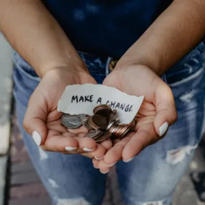 Photo: hands offering money with a note that reads "Make a Change"