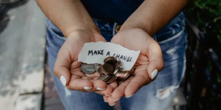 Photo: hands offering money with a note that reads "Make a Change"