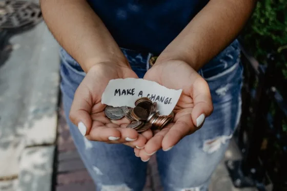 Photo: hands offering money with a note that reads "Make a Change"