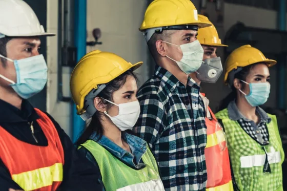 Photo: Men and women warehouse workers standing next to each other while wearing protective masks.