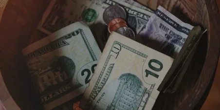 Photo: Cash and coins placed in a wooden donation bowl.