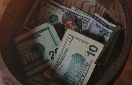 Photo: Cash and coins placed in a wooden donation bowl.