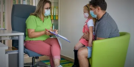 Photo: Case worker wearing a pandemic mask meeting with father and child also wearing pandemic masks for a services assessment