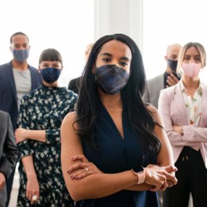 Photo: Group of people standing with arms crossed and wearing face masks.