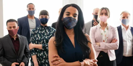 Photo: Group of people standing with arms crossed and wearing face masks.