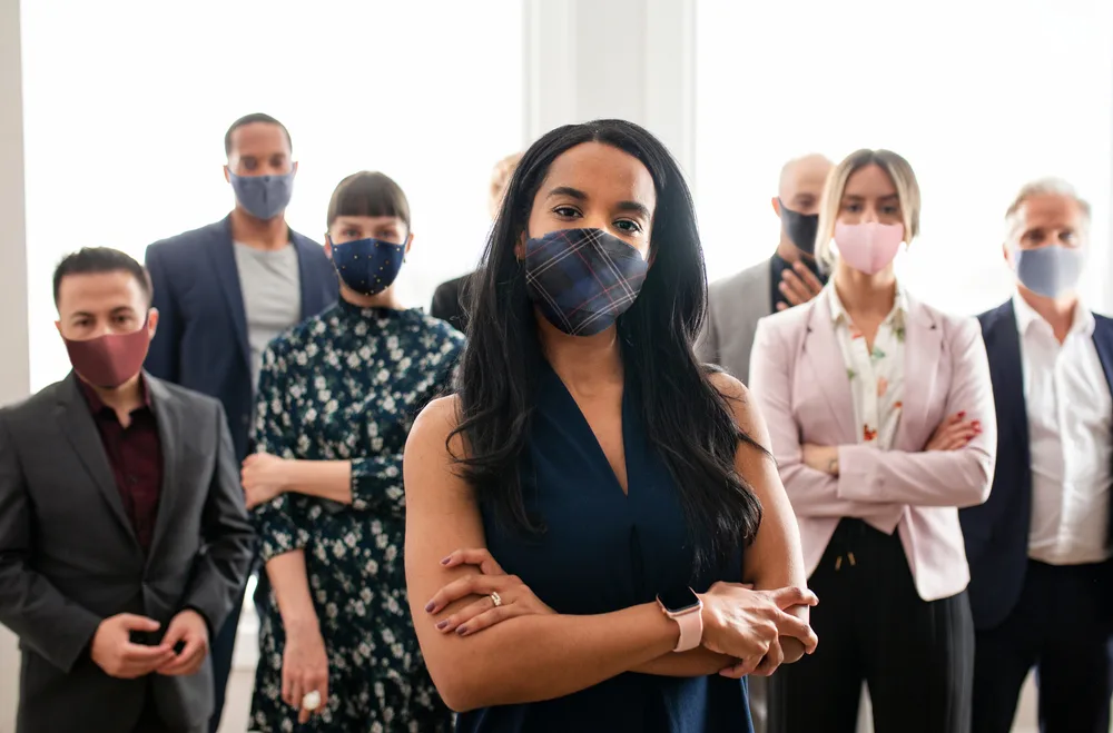 Photo: Group of people standing with arms crossed and wearing face masks.