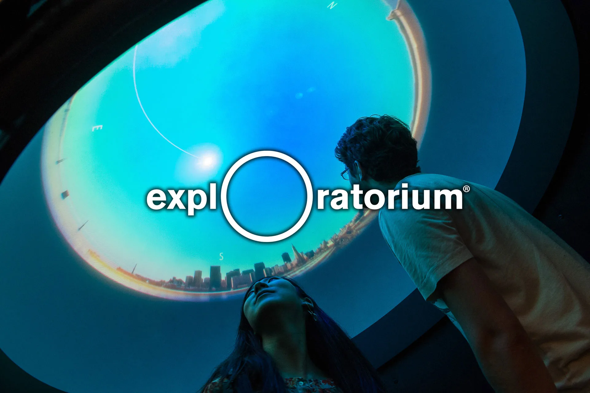 Image: Exploratorium logo with image of visitors looking at an exhibit