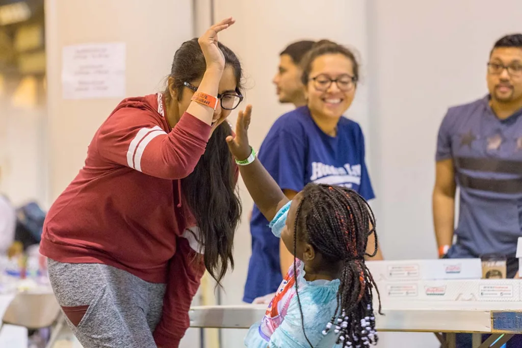 Support workers and volunteers play with a young girl at a shelter Implementation of Salesforce
