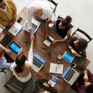 Team collaborating on devices around a table