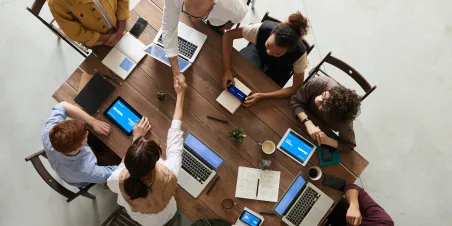 Team collaborating on devices around a table