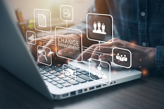 Hands on laptop with change management concept graphics