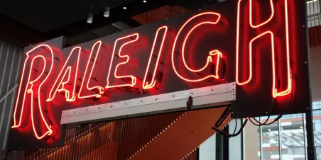 Picture of lit neon sign that says Raleigh