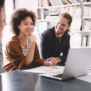 Diverse team of individuals working around a laptop computer