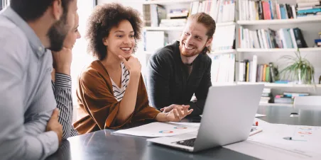 Diverse team of individuals working around a laptop computer