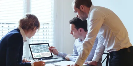 Three people gathered around a laptop screen