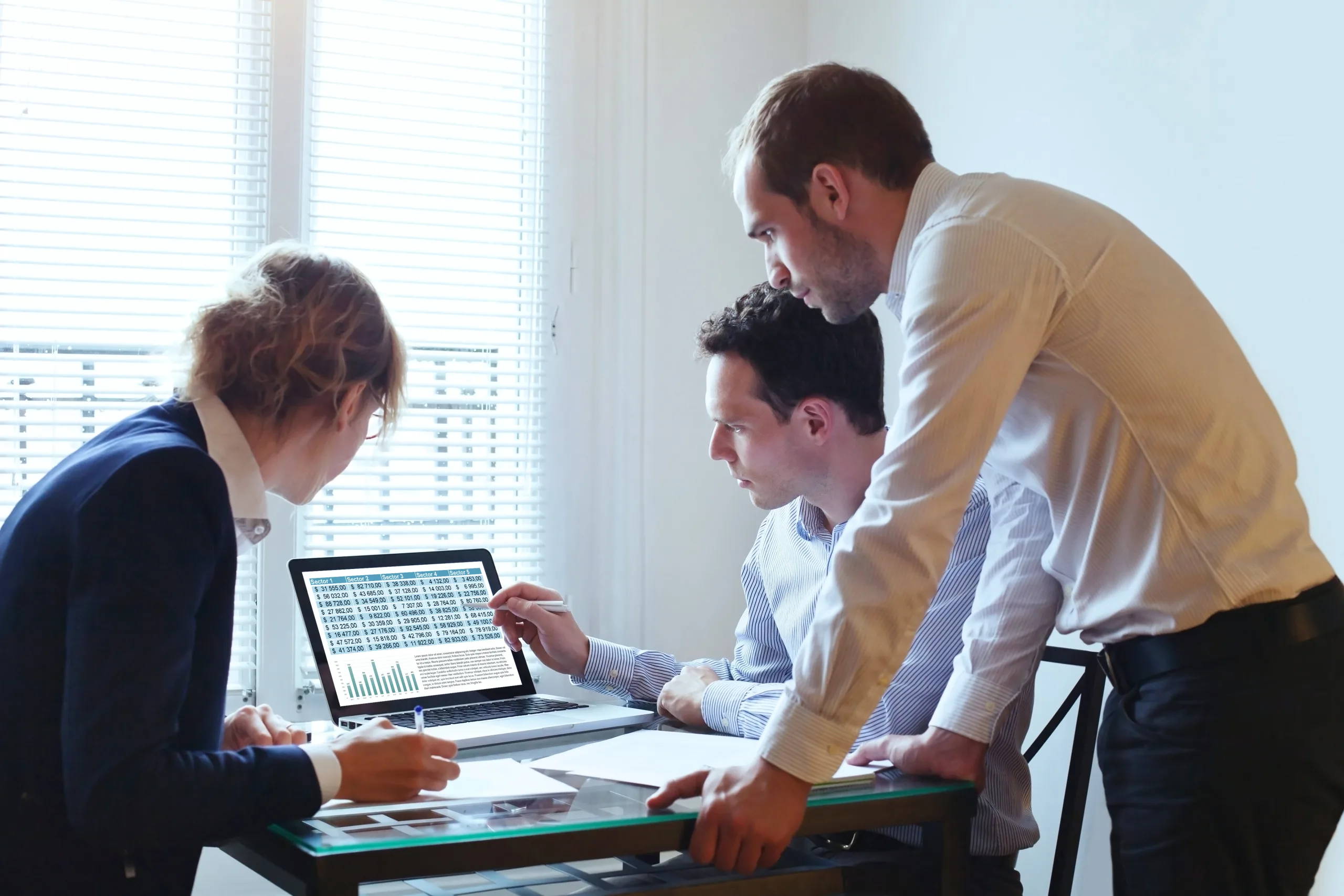 Three people gathered around a laptop screen